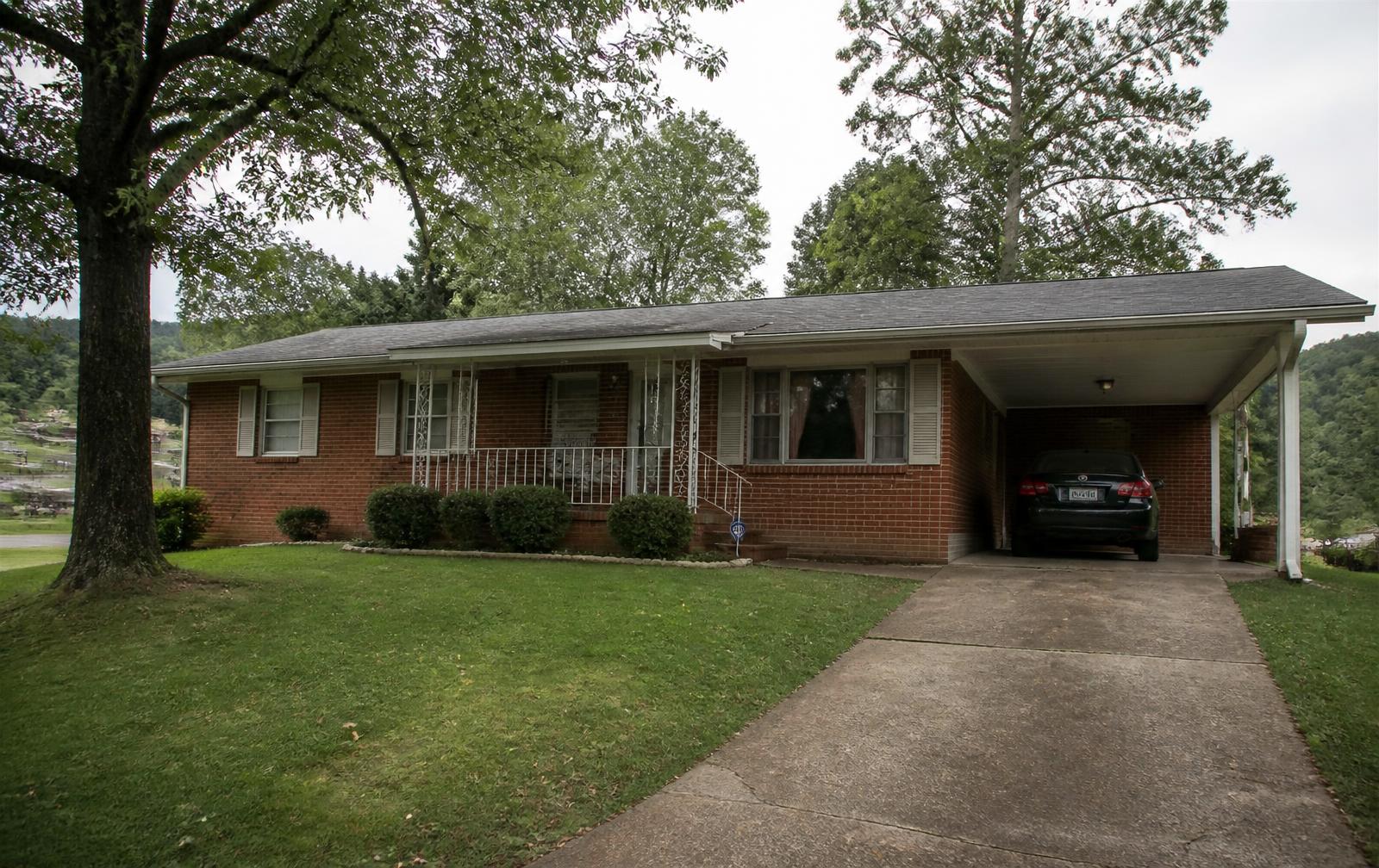 A brick ranch house with a carport on a wooded lot in North Alabama